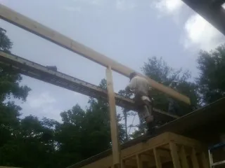 Carpenter setting a ridge beam over a new addition frame — Ice Dam Removal by Roofing Brothers in Swannanoa