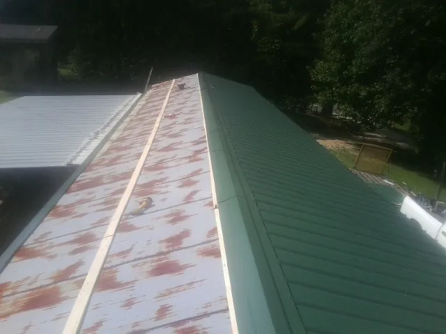 Old rusted panels beside newly installed green metal roofing — Wind Damage Roof Repair by Roofing Brothers in Swannanoa