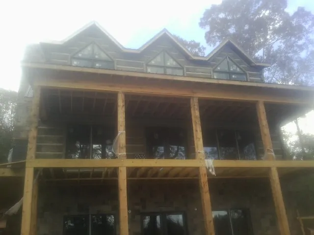 Dormers and porch framing on a large log home under construction — Roof Coating work by our crew in Swannanoa